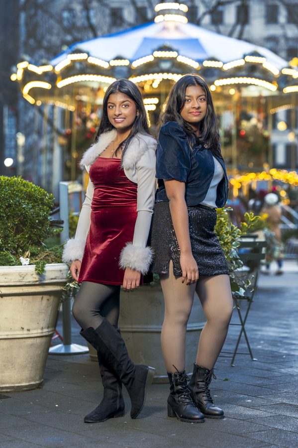Sisters posing in front of a holiday carousel